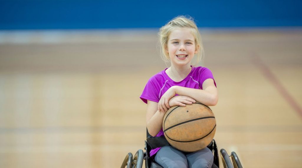 A young girl in a wheelchair with a basketball